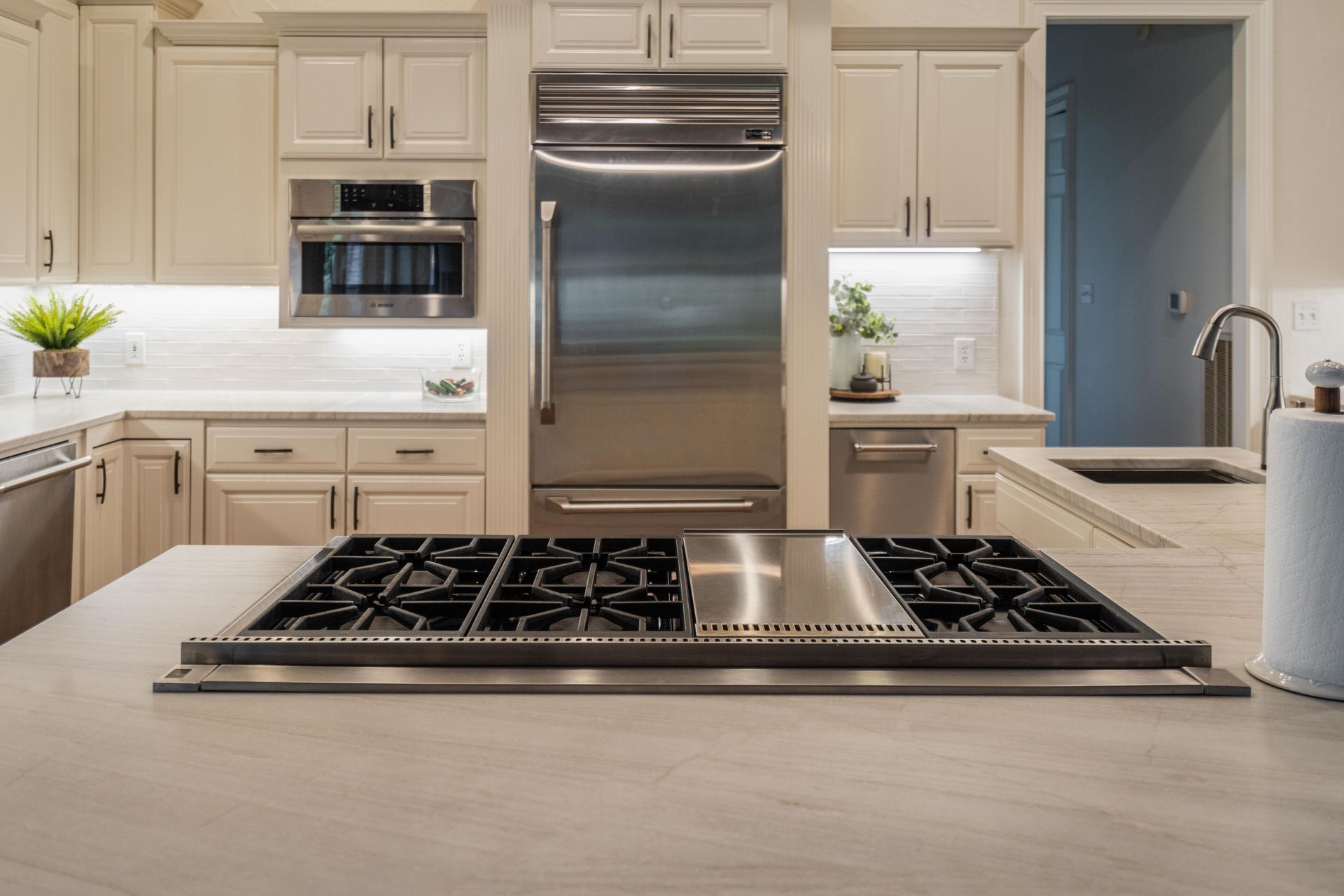 Modern kitchen with white cabinets, stainless steel appliances, and a gas cooktop on a large island