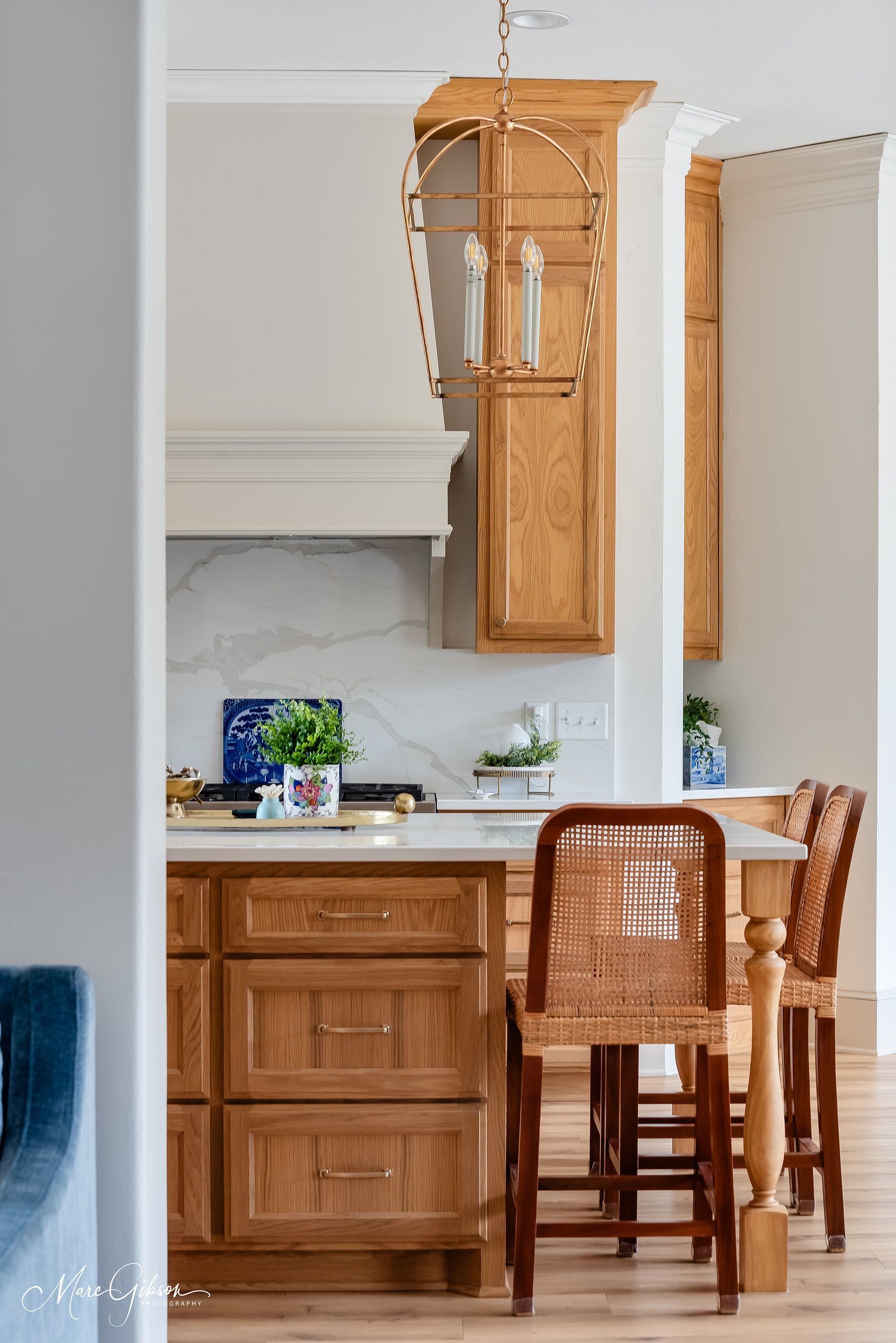 Bright kitchen with wooden island, white cabinets, and woven stools in a sunlit home interior