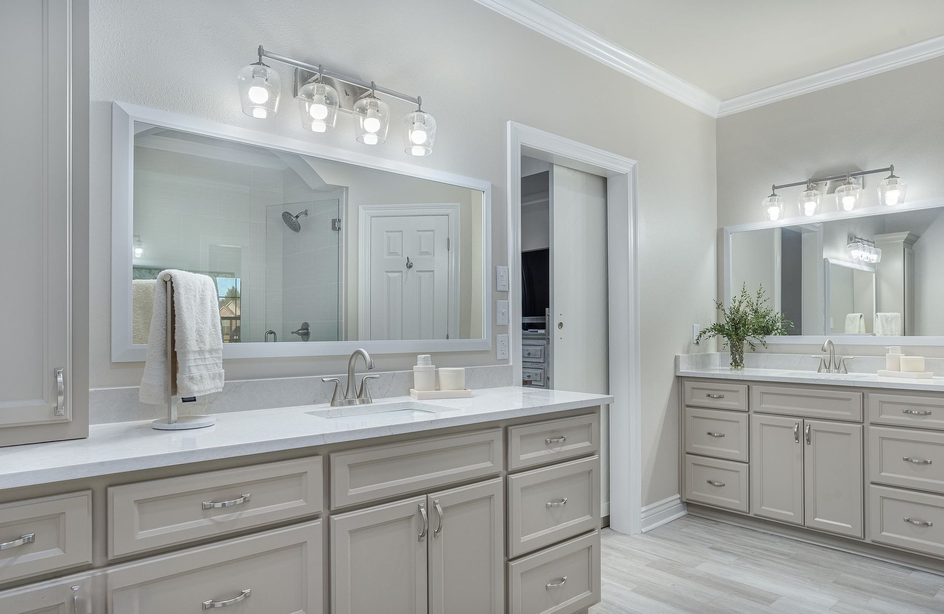 Bright modern bathroom with double vanity, large mirrors, and white-gray cabinetry