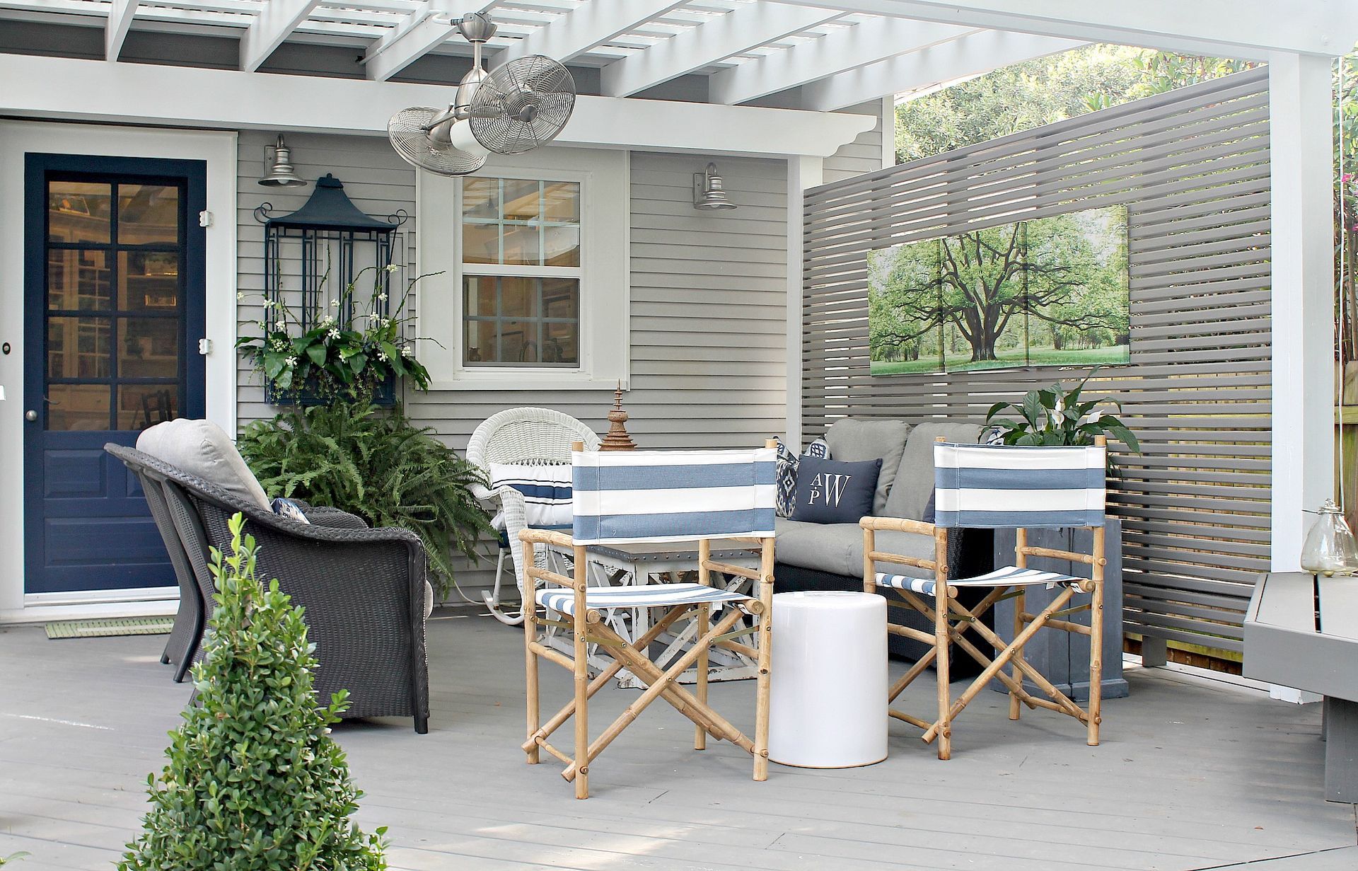 Outdoor patio with white dining chairs, wooden table, wicker sofa, and potted plants under a pergola