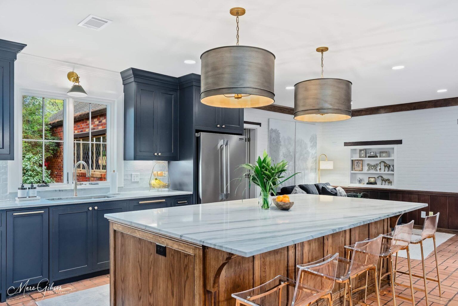 Modern kitchen with blue cabinets, marble island, woven stools, and two pendant lights