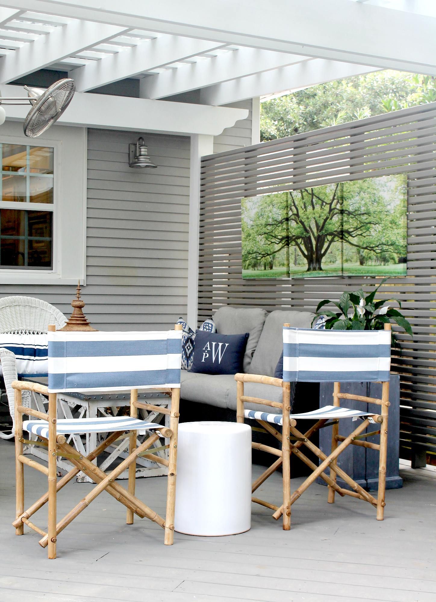 Outdoor patio seating area with blue cushions, wooden chairs, and a white side table under a pergola