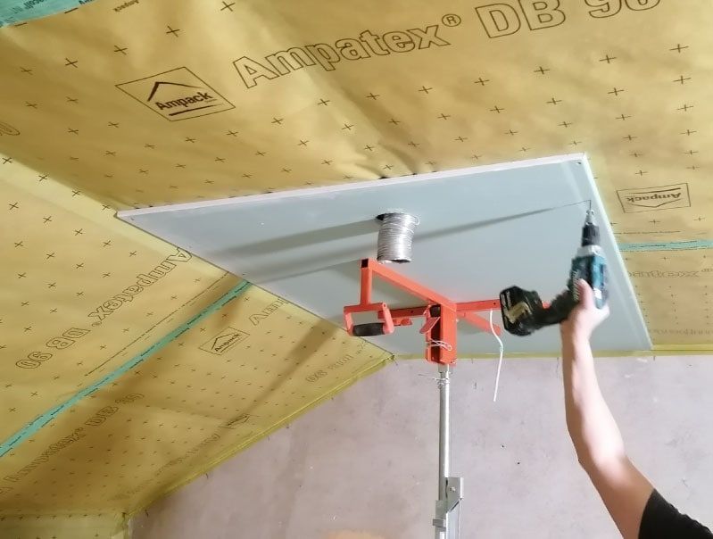Eine Person installiert Trockenbauwände an einer Decke.