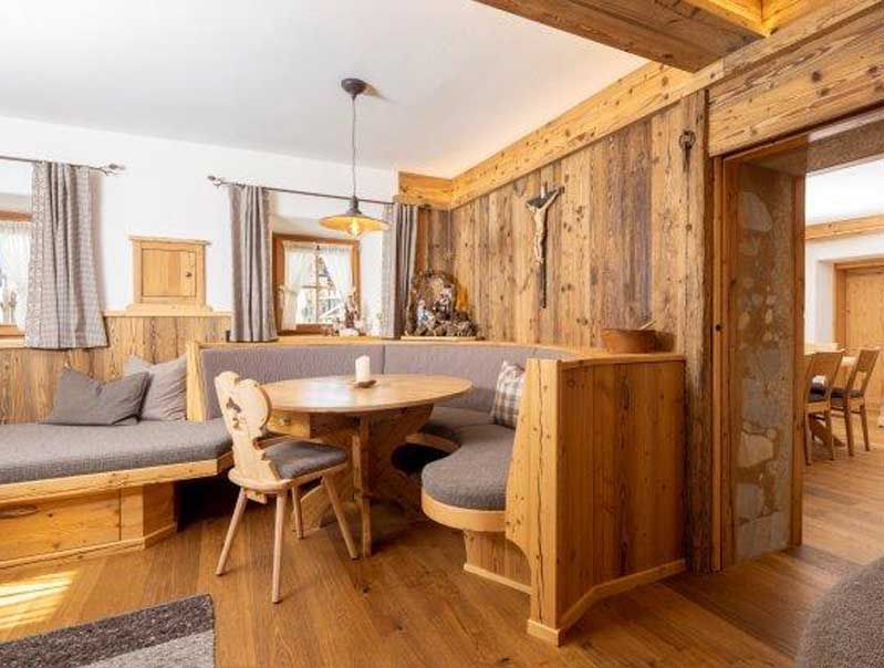 Gemütlicher Essbereich aus Holz mit eingebauter Sitzbank, rundem Tisch und Stuhl in rustikalem Hüttenstil.