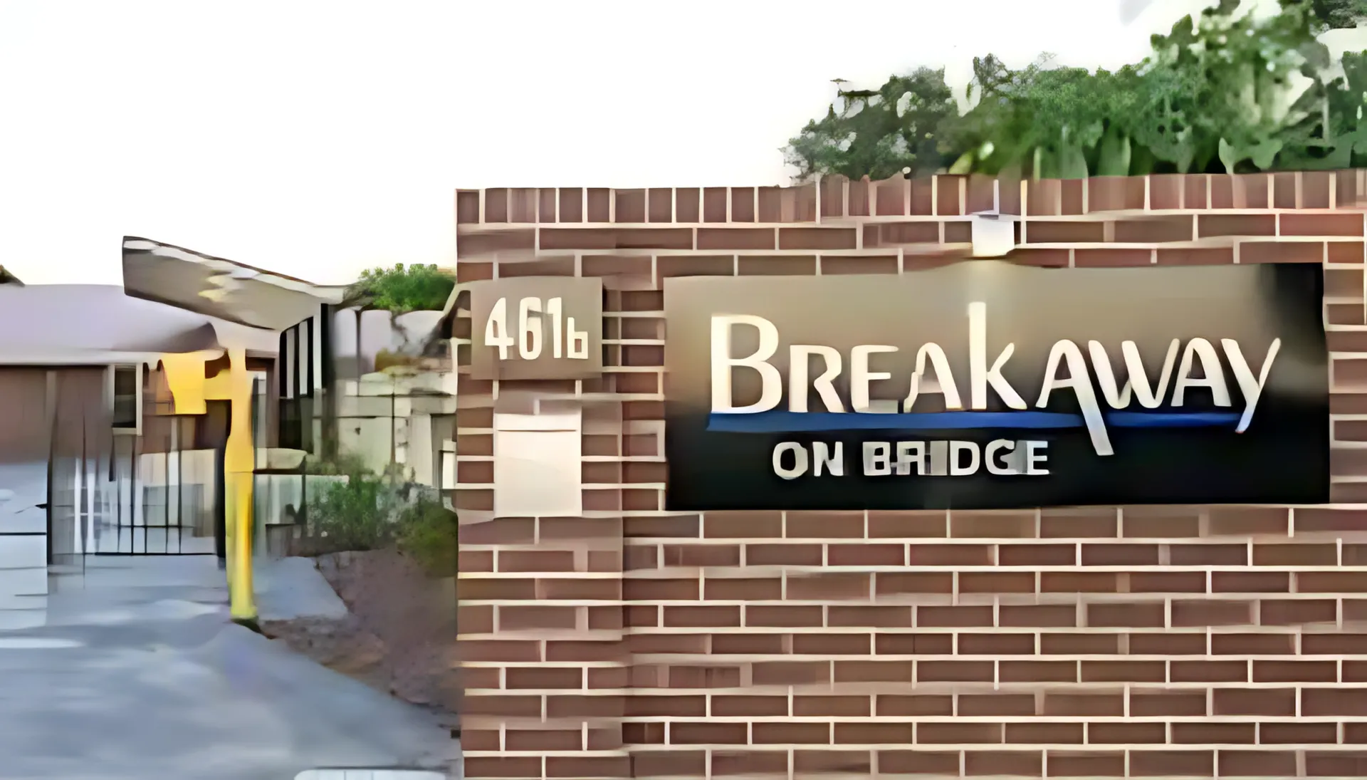 Brick sign reading “Breakaway on Bridge” beside a gated entrance and pathway.