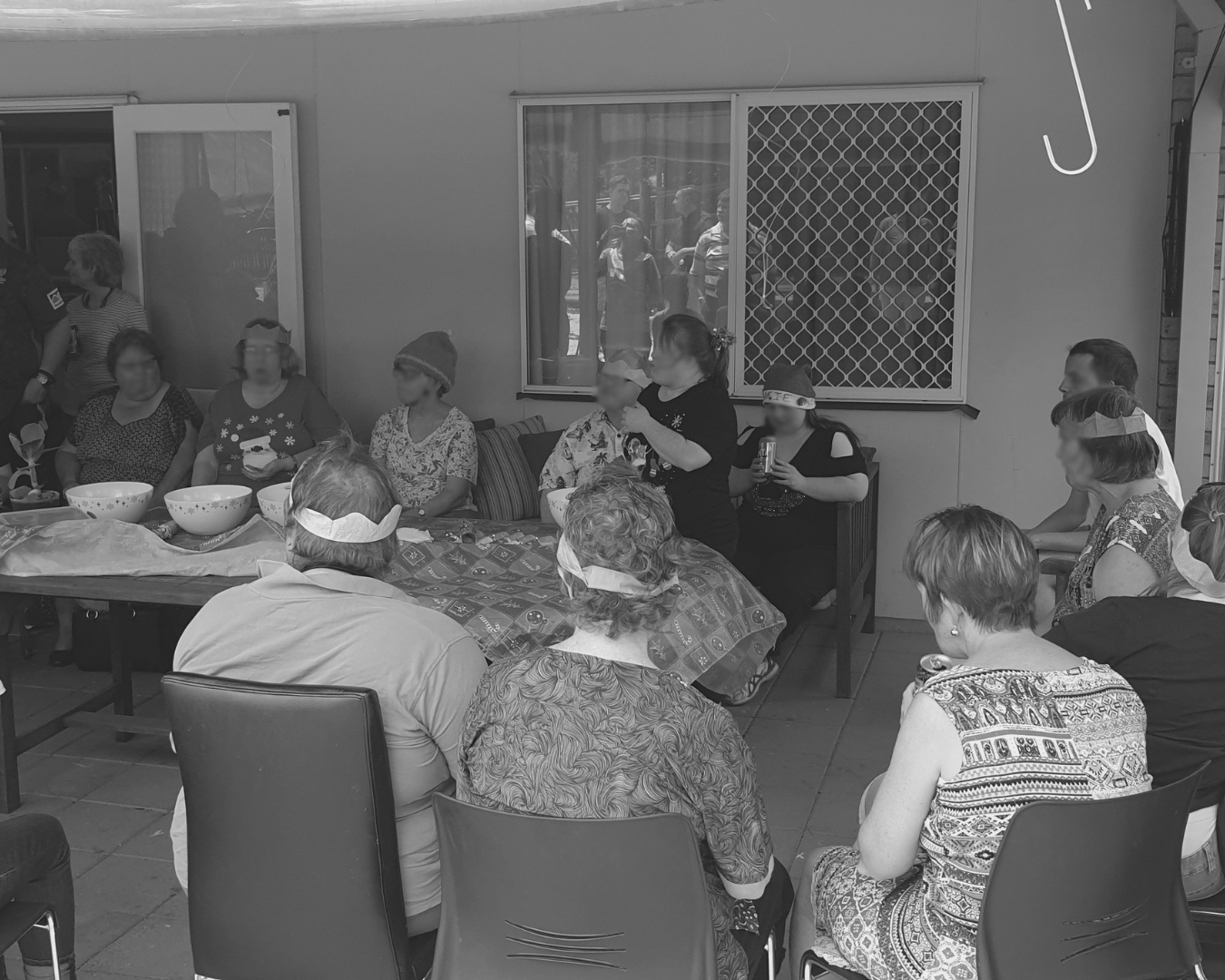 People seated in a room, gathered around tables during a small indoor meeting or social event.