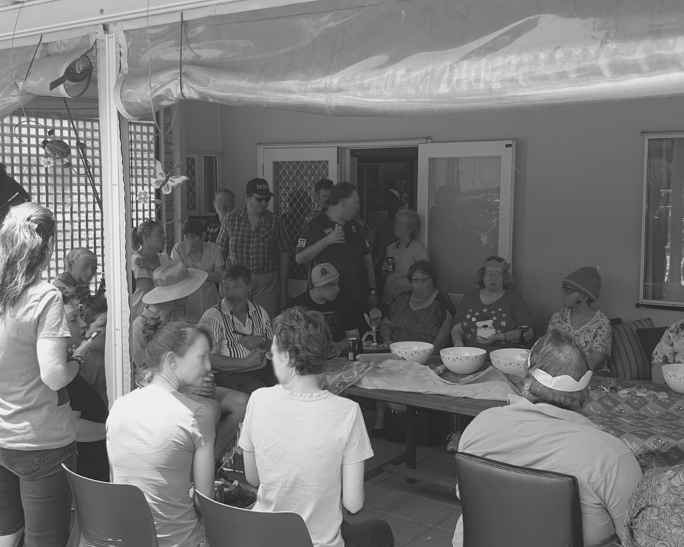 People seated around a table under a patio tent at a casual outdoor gathering