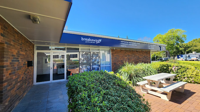 Storefront with blue awning, glass doors, brick walls, and a picnic table outside in a sunny courtyard