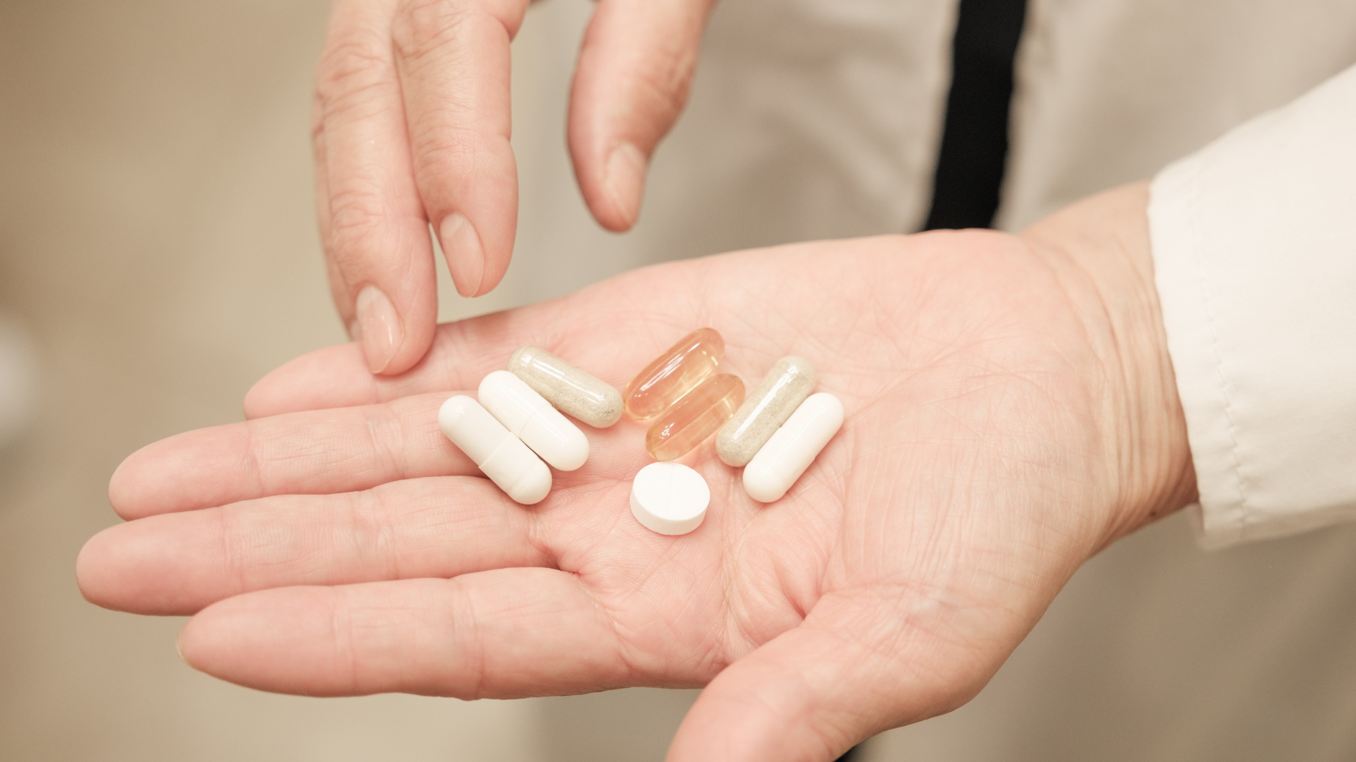 Hand holding pills of different shapes and colors.