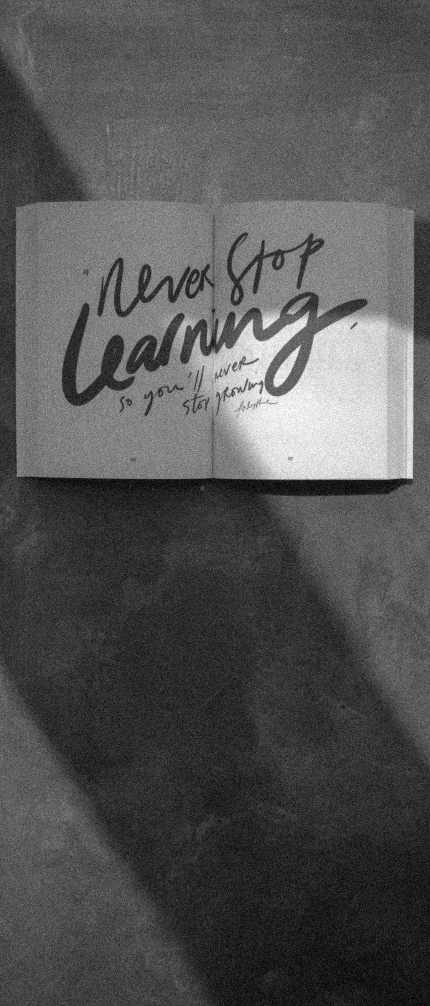 Small “Never Stop Learning” sign on a dark textured background.