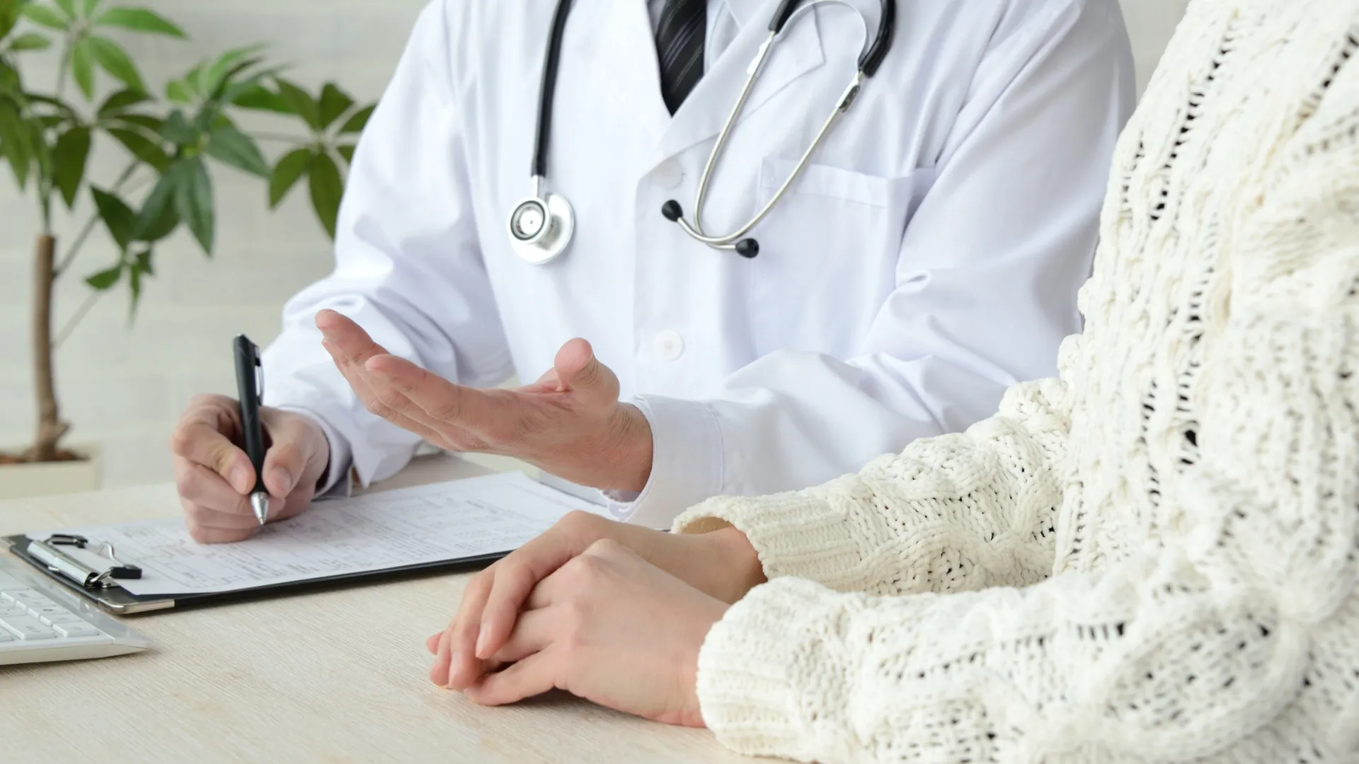 Doctor consulting with a patient at a desk, taking notes during a medical visit.