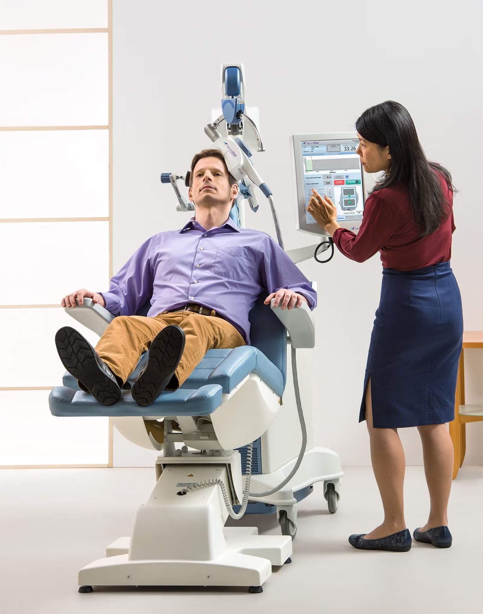 Patient reclines in a dental chair while a clinician operates a dental X-ray machine in a bright exam room