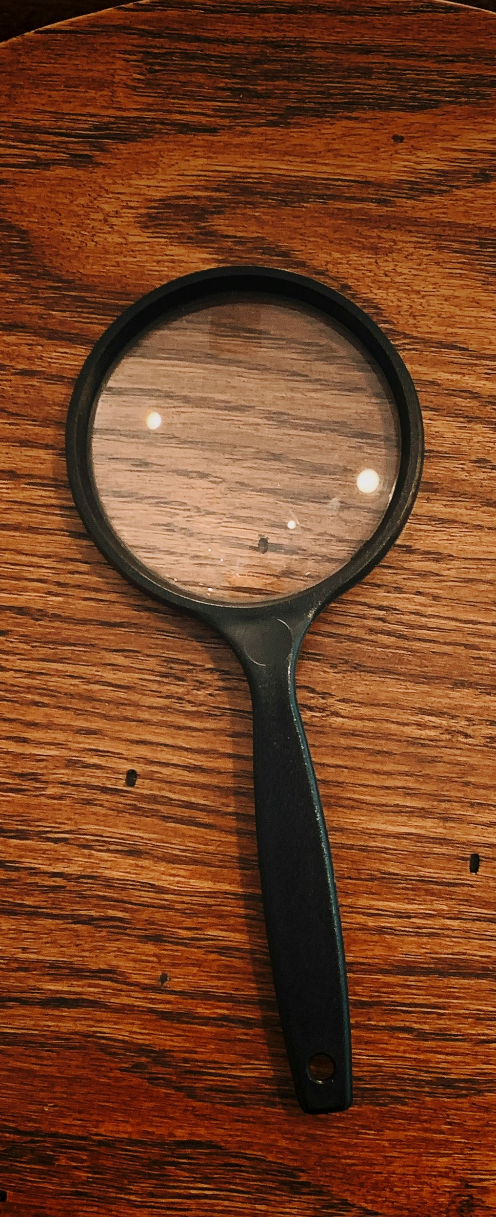 Black magnifying glass on a wooden surface