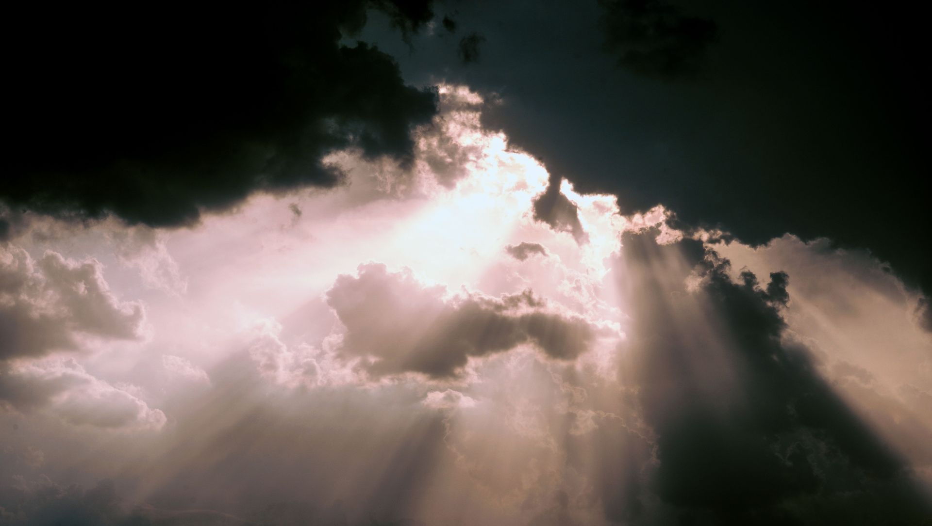 Sunbeams breaking through dark clouds over a stormy sky