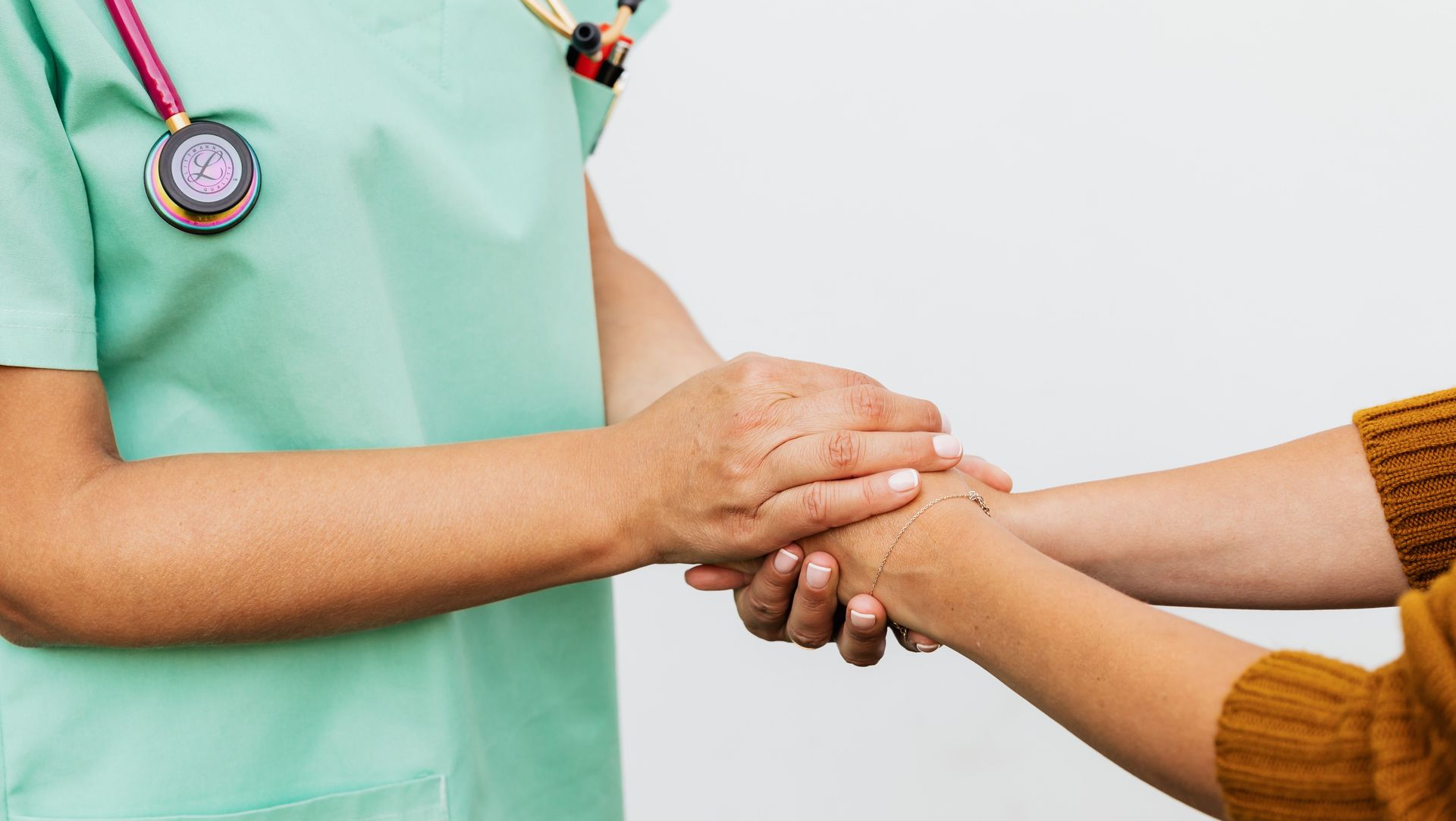 Healthcare worker holding a patient’s hand in a reassuring gesture