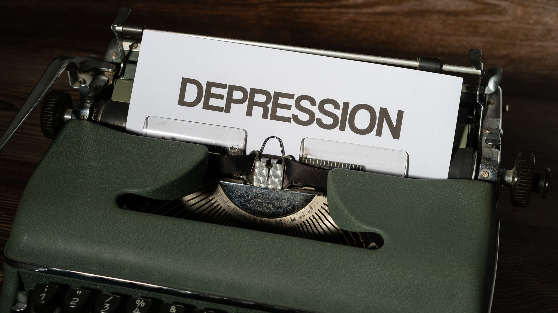 Typewriter with paper reading “DEPRESSION” on a dark desk.