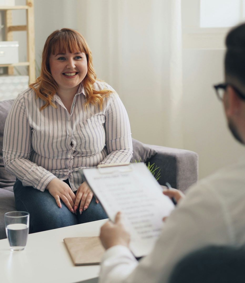 Woman smiling during a counseling session with a therapist holding notes in a bright office