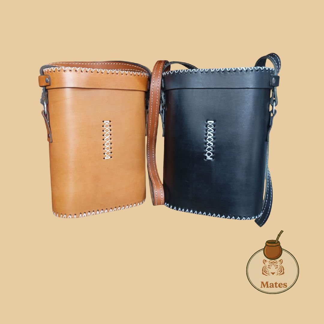 Dos bolsos bandolera de piel, uno tostado y otro negro, con pespuntes en contraste, sobre fondo marrón.