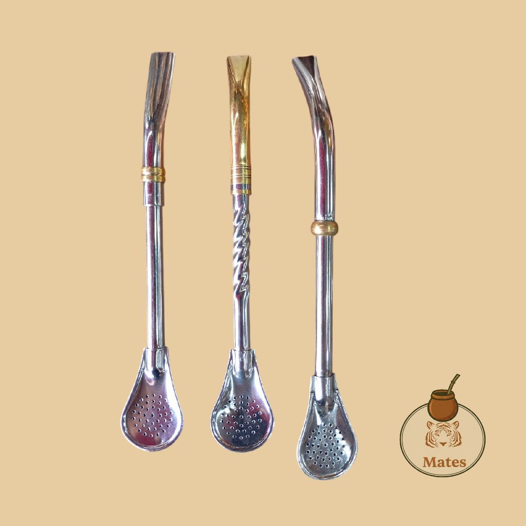 Tres bombillas metálicas (pajitas para yerba mate) sobre fondo beige, cada una con un diseño diferente.