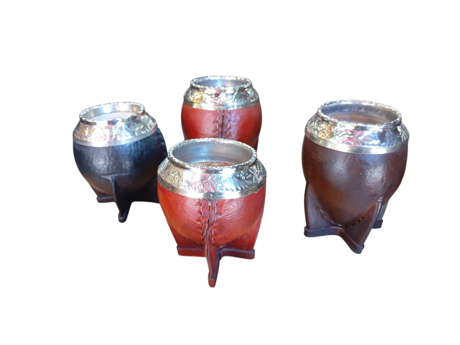 Cuatro calabazas para mate con bases de cuero y bordes metálicos ornamentados, dispuestas sobre un fondo blanco.