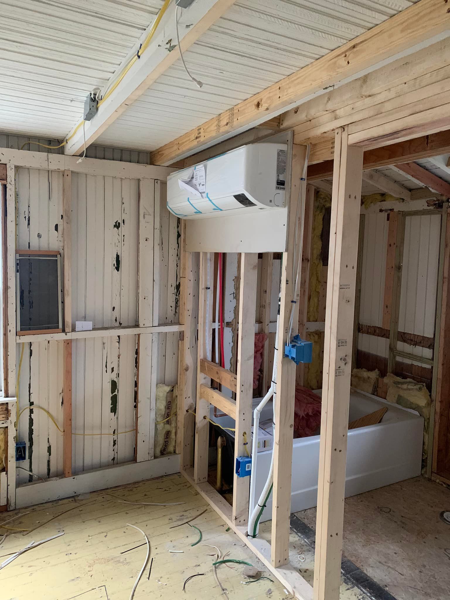 A room under construction with a ceiling fan hanging from the ceiling.