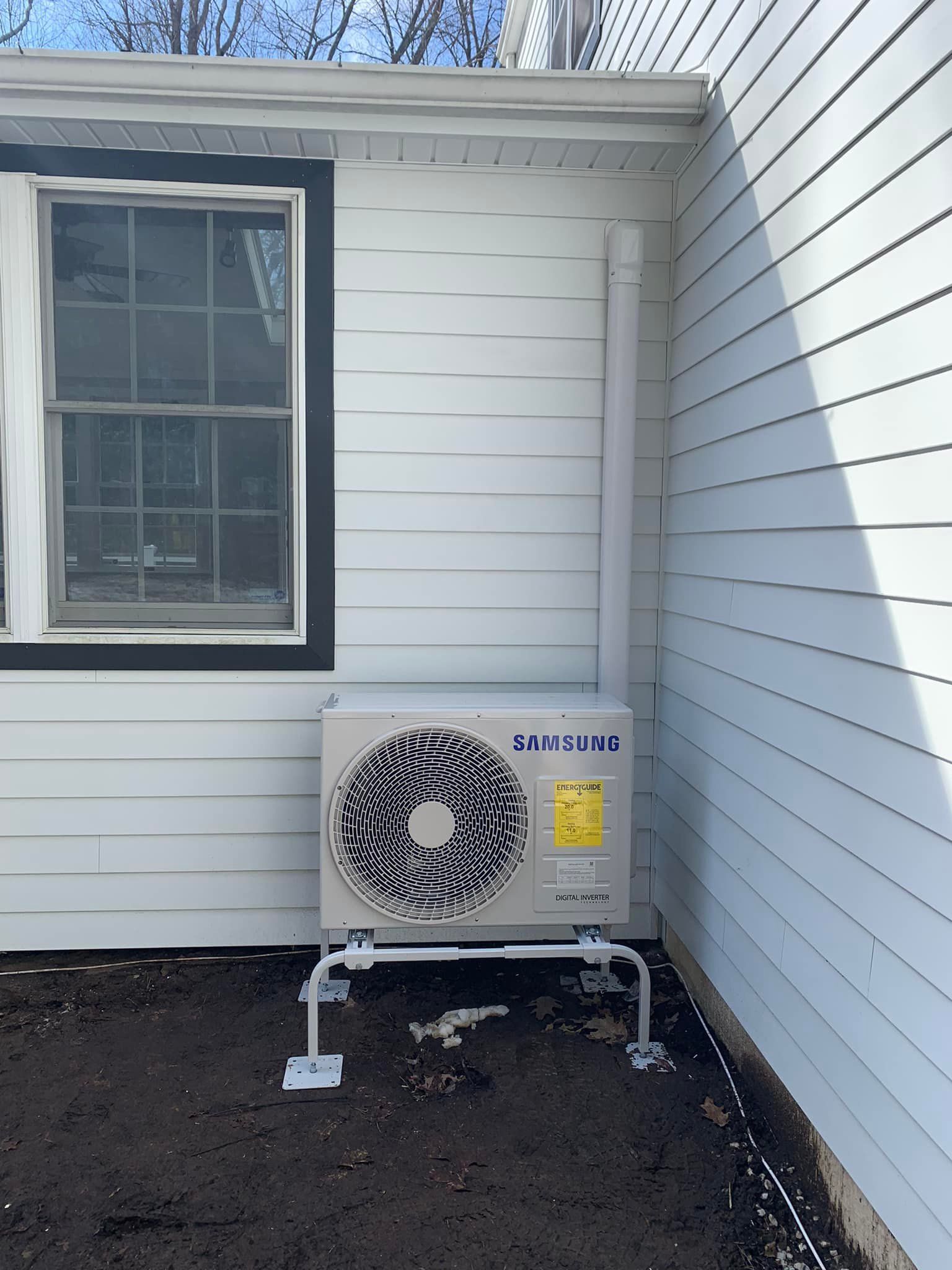 A samsung air conditioner is mounted on the side of a house
