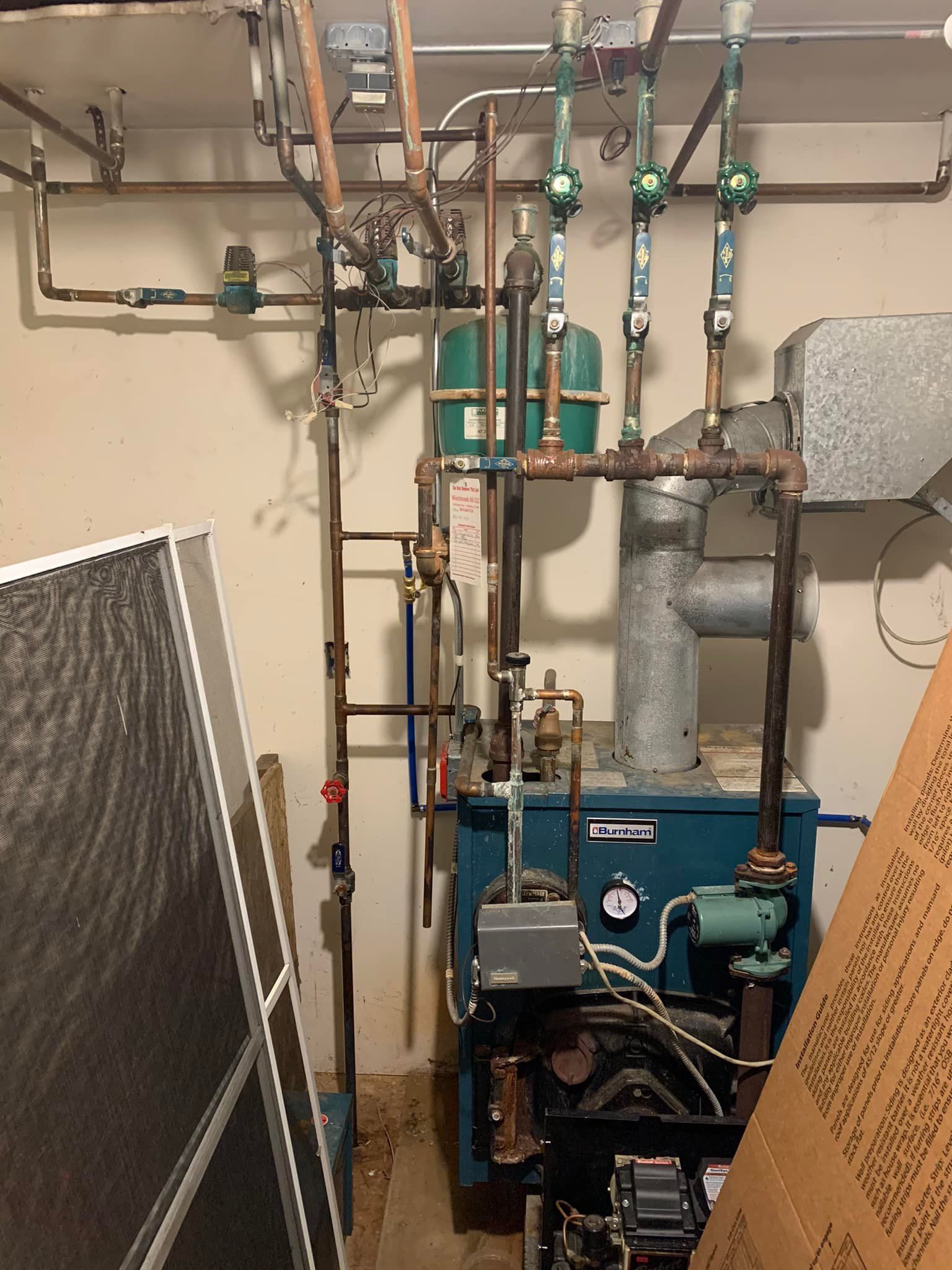 A room with a blue boiler and a lot of pipes.