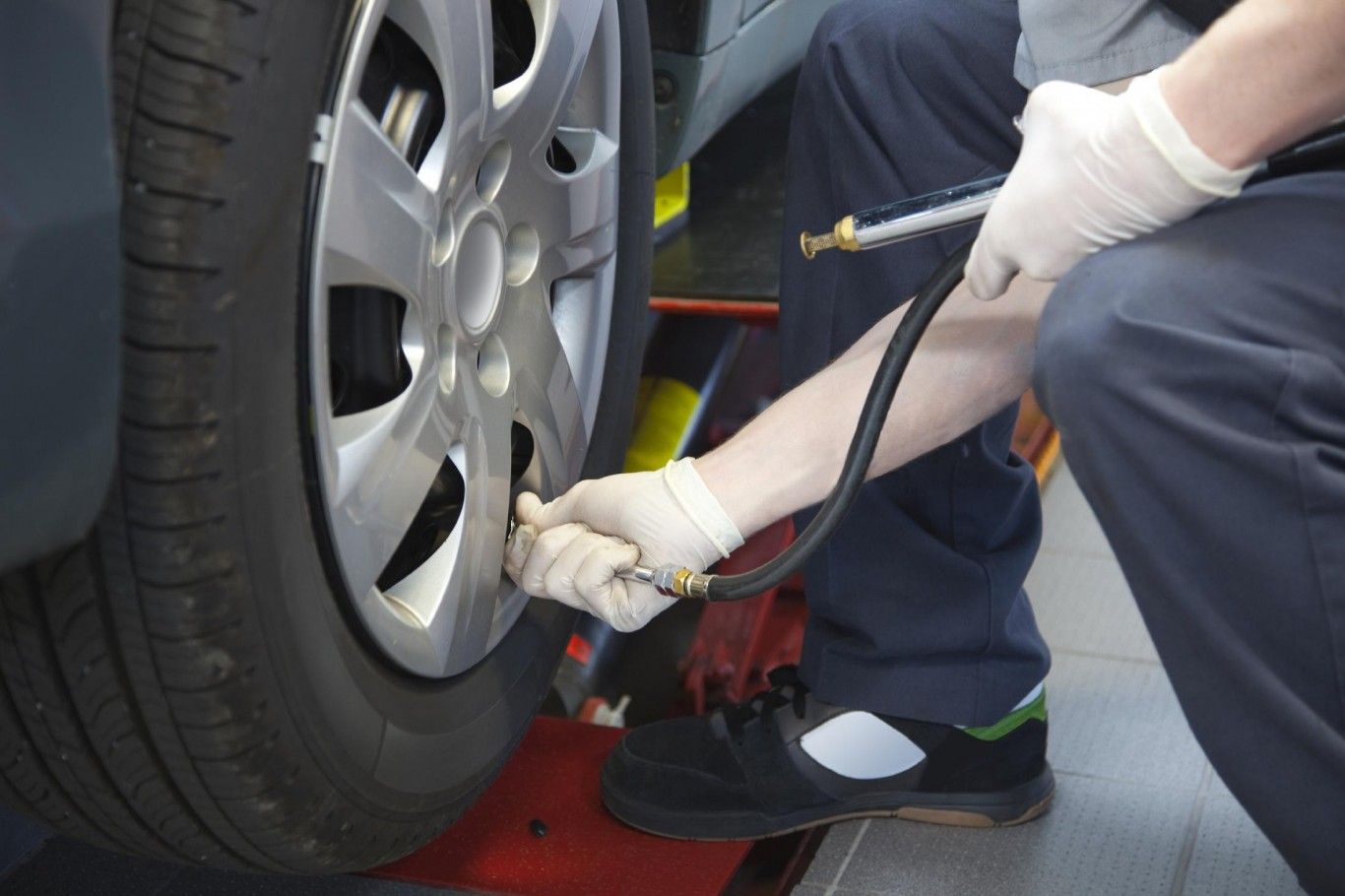 Mechanic inflating a car tire with an air hose during roadside service