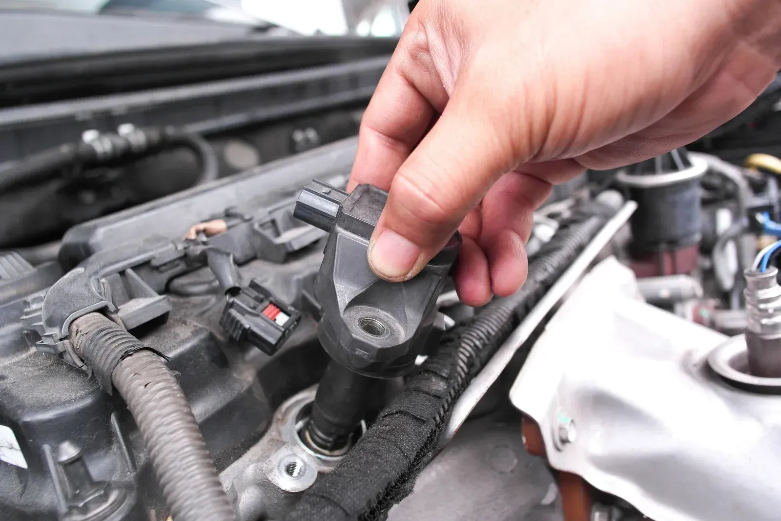 Hand installing an ignition coil on a car engine