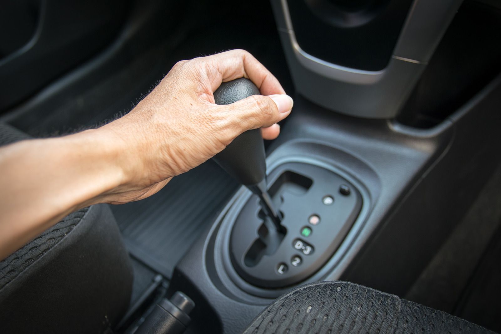 Hand shifting an automatic car gear selector in a black center console