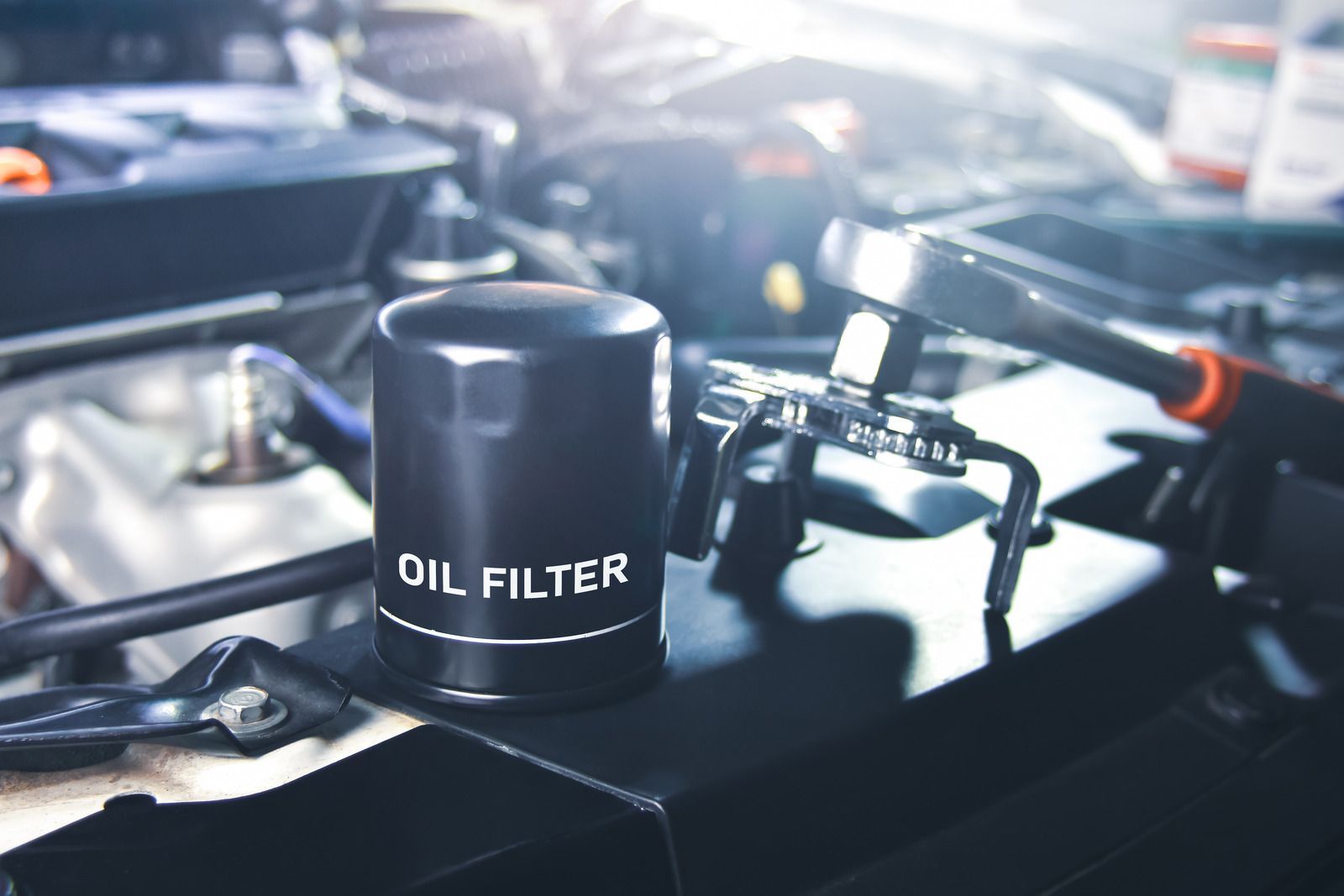 Black oil filter on an engine with blurred car parts in the background