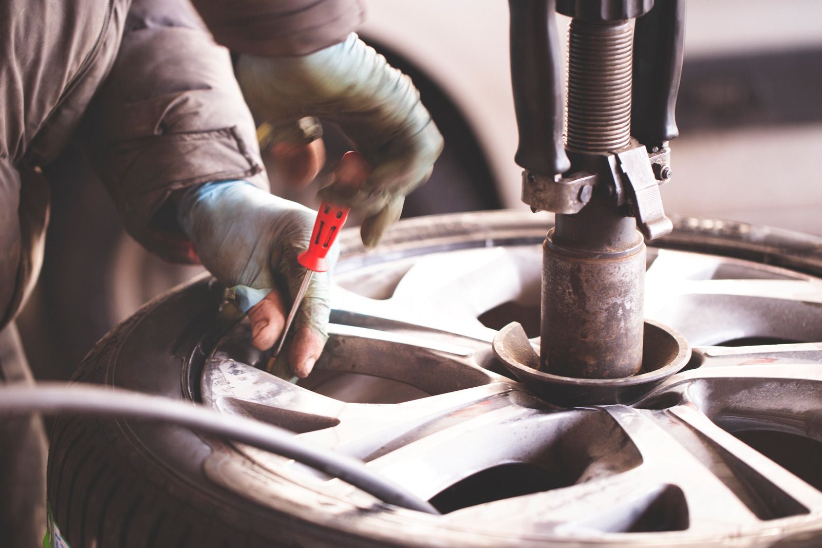 Mechanic using a red tool to work on a car wheel hub in a garage