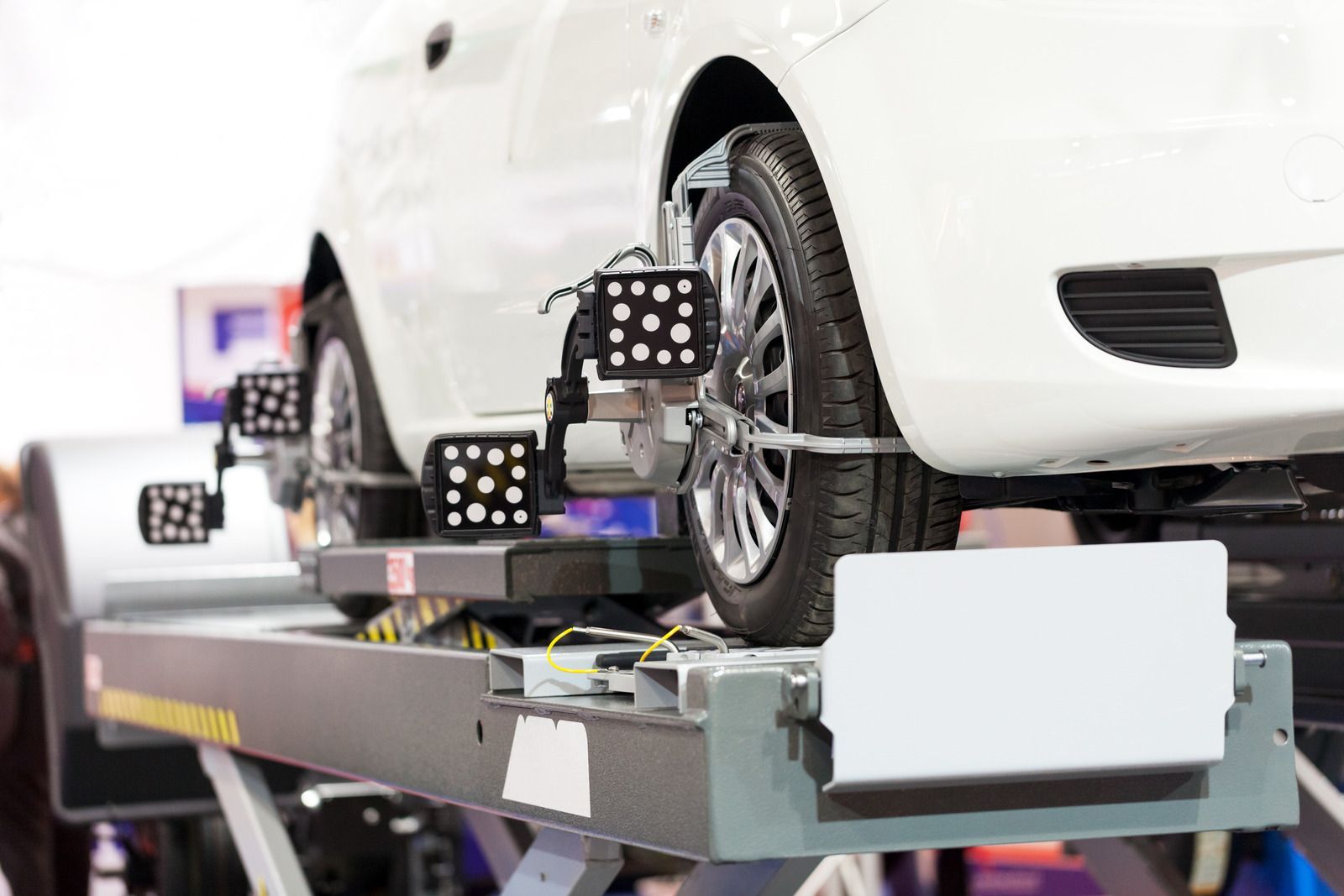 White car on a wheel alignment machine with measurement sensors attached