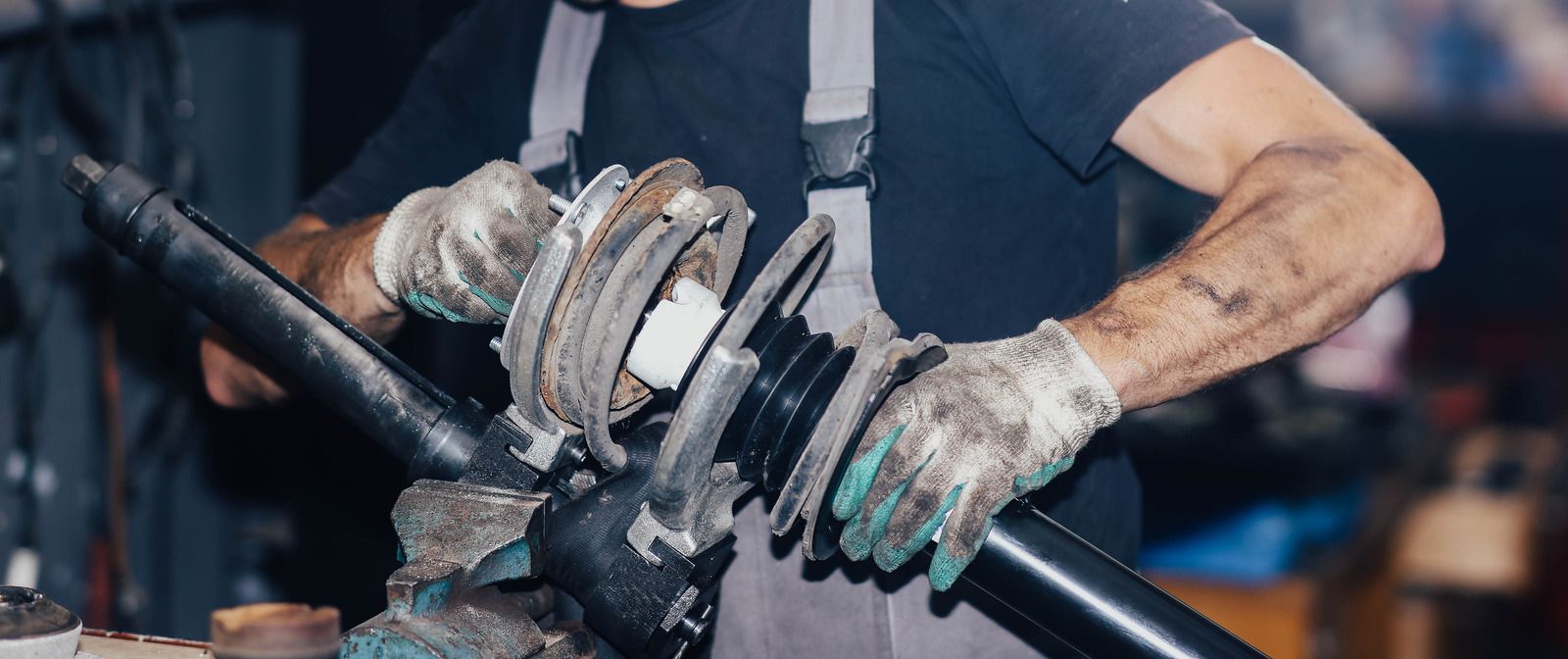 Car wheel and brake assembly beside a mechanic holding a black suspension strut mount