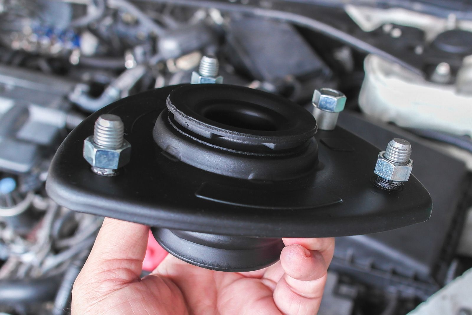 Hand using a red ratchet wrench to tighten a car engine bolt under the hood