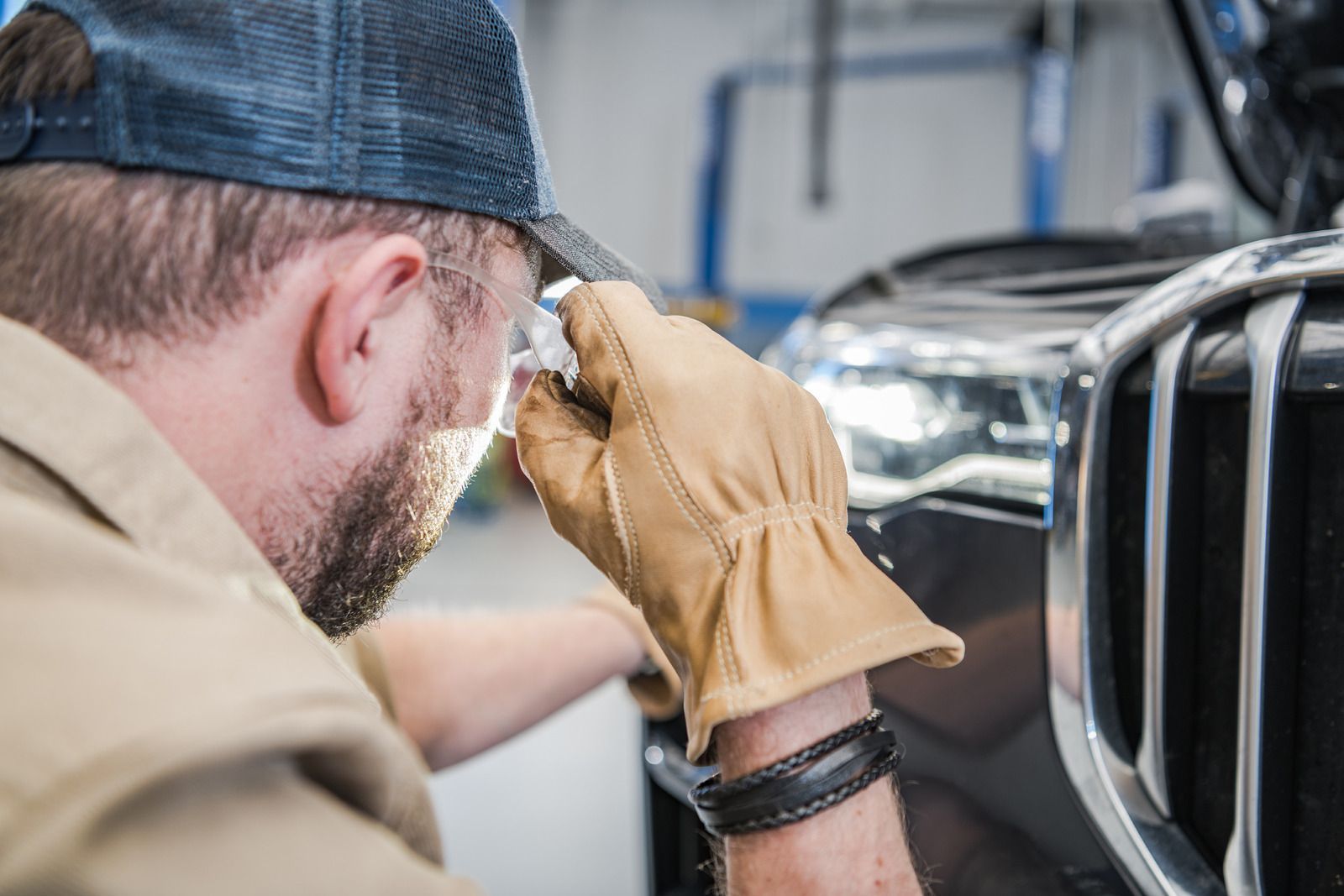Mechanic inspecting a car grille with a magnifying glass in a garage