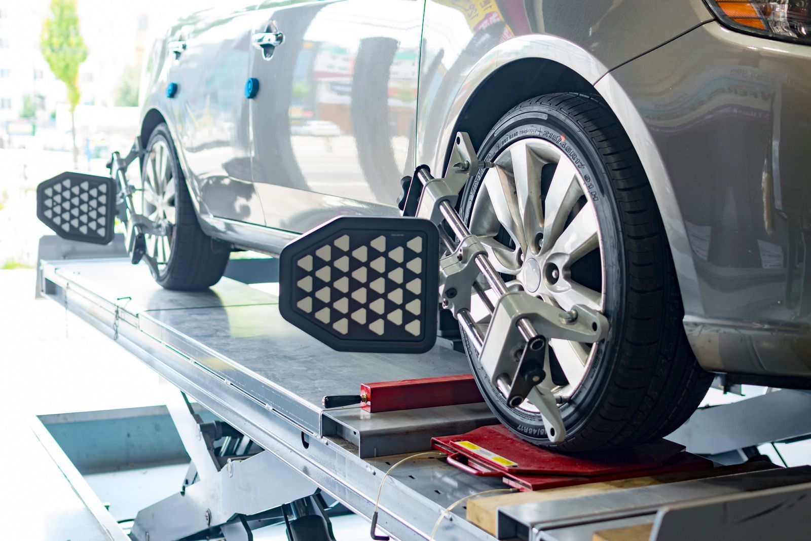 Car on wheel alignment rack in auto shop, with clamps on the tires
