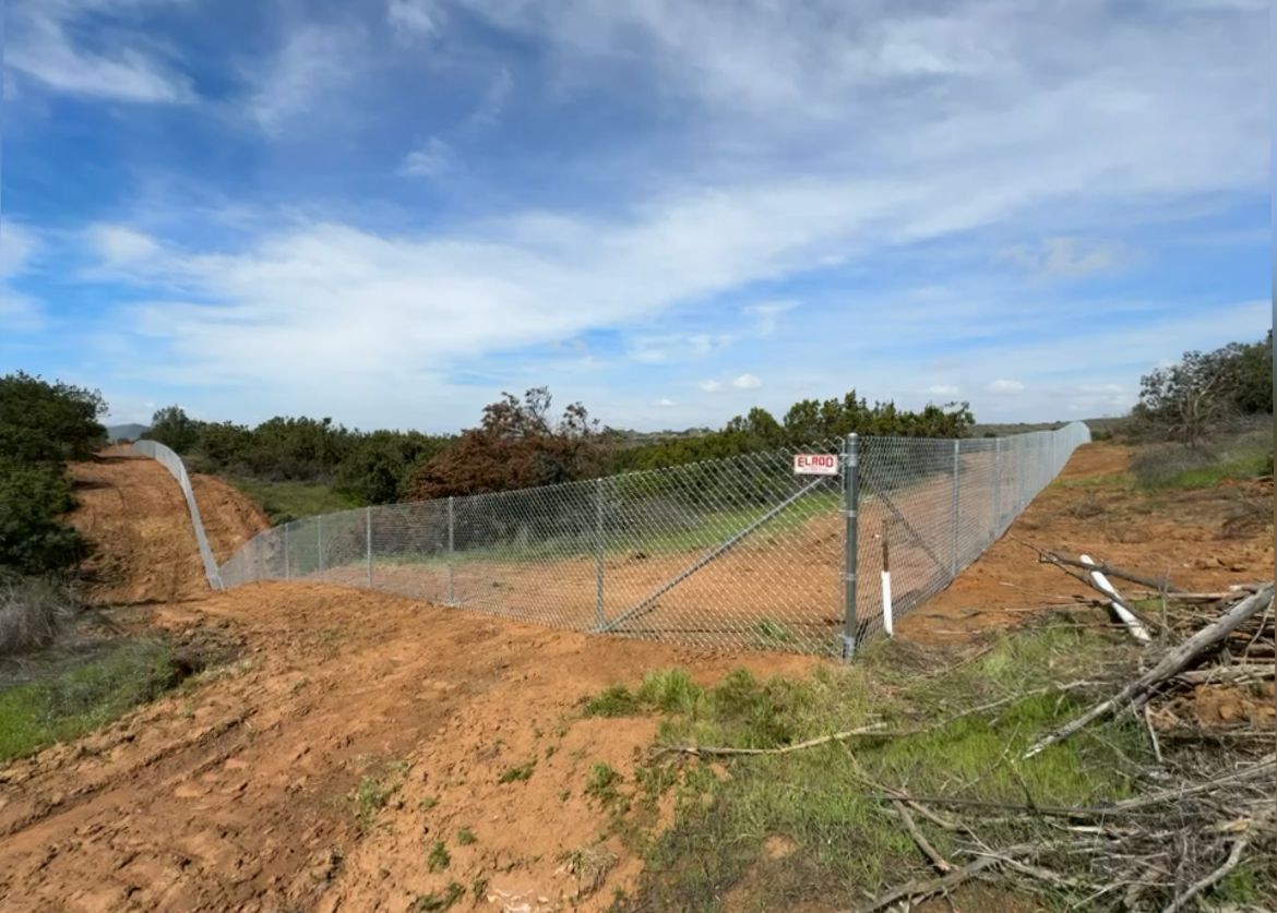 A Fence Is Surrounding a Dirt Road in a Field — Riverside, CA — Elrod Fence Co