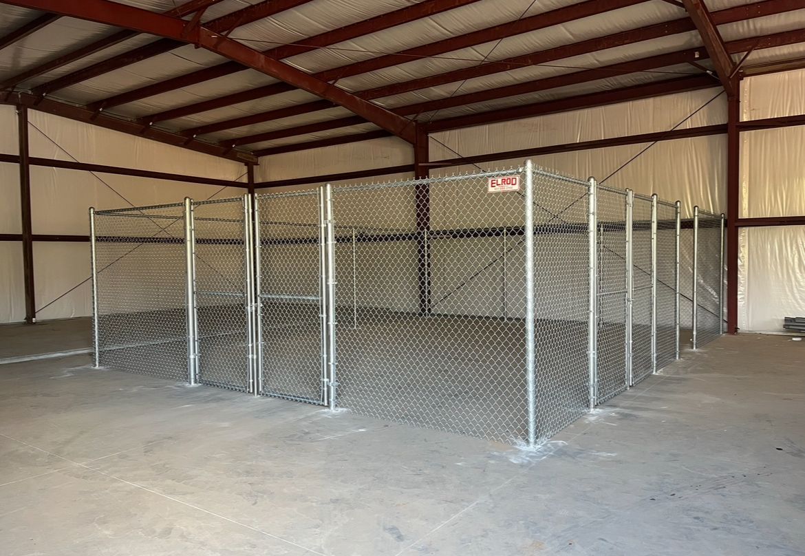 Chain-link storage cages inside a large warehouse building.
