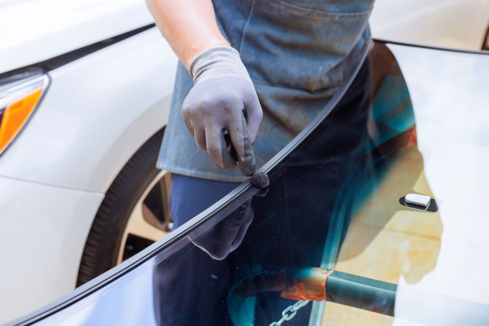 Person applying window tint film to a car side window during an automotive glass service.