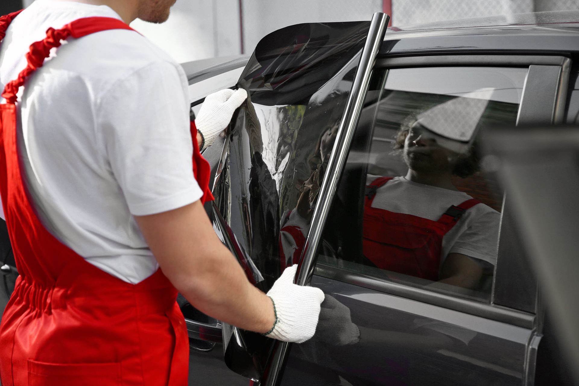 Male worker tinting car window outdoors.