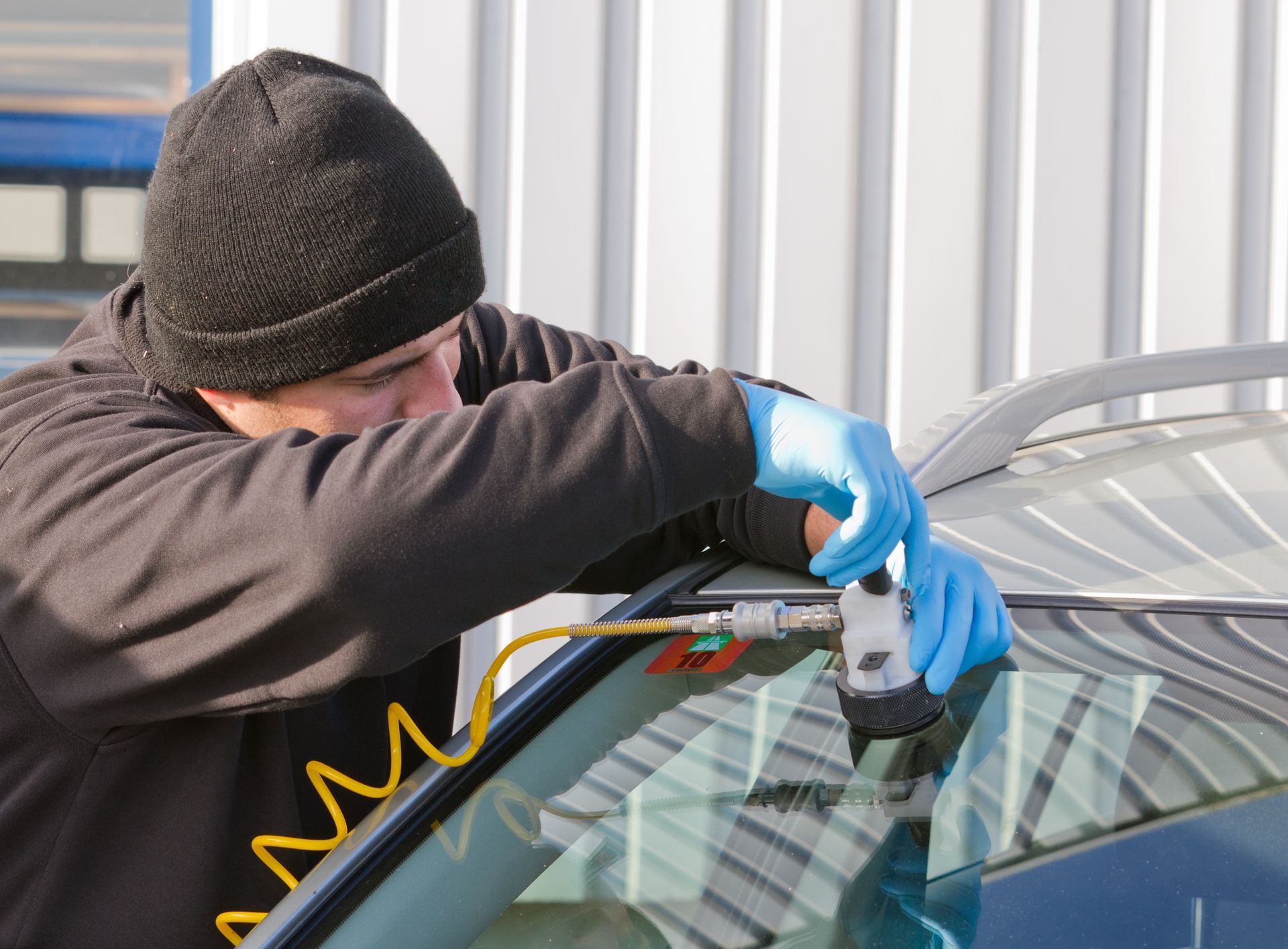 Auto glass technician repairing a car windshield with a vacuum glass repair tool.