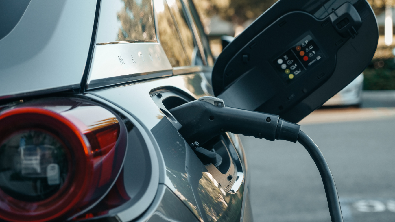 Electric car charging with black charging cable plugged into car.