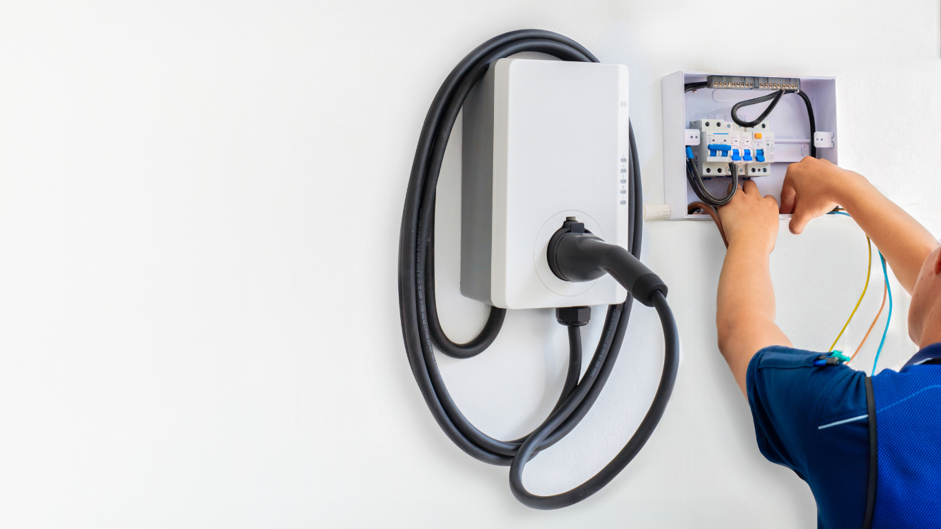 Child installing electrical wiring in a wall-mounted EV charger box.