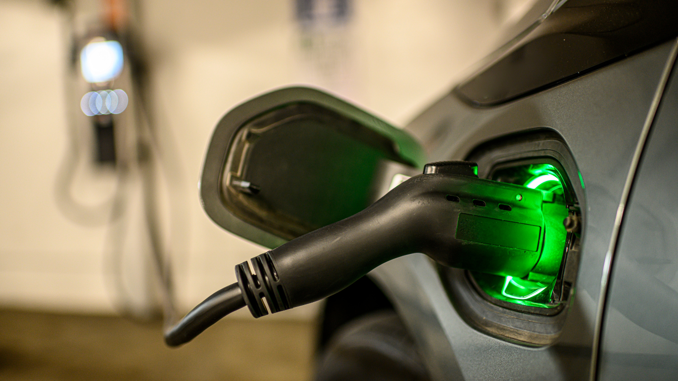 Electric vehicle being charged; green light indicates charging in progress.