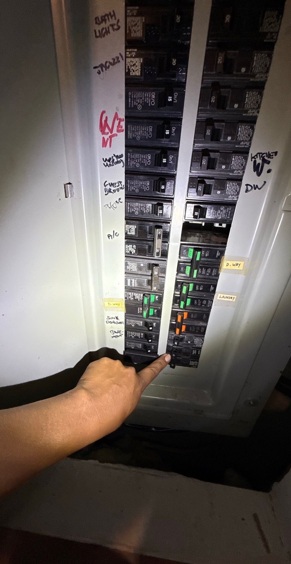 Hand touching a circuit breaker panel, activating a switch. Electrical wiring visible.