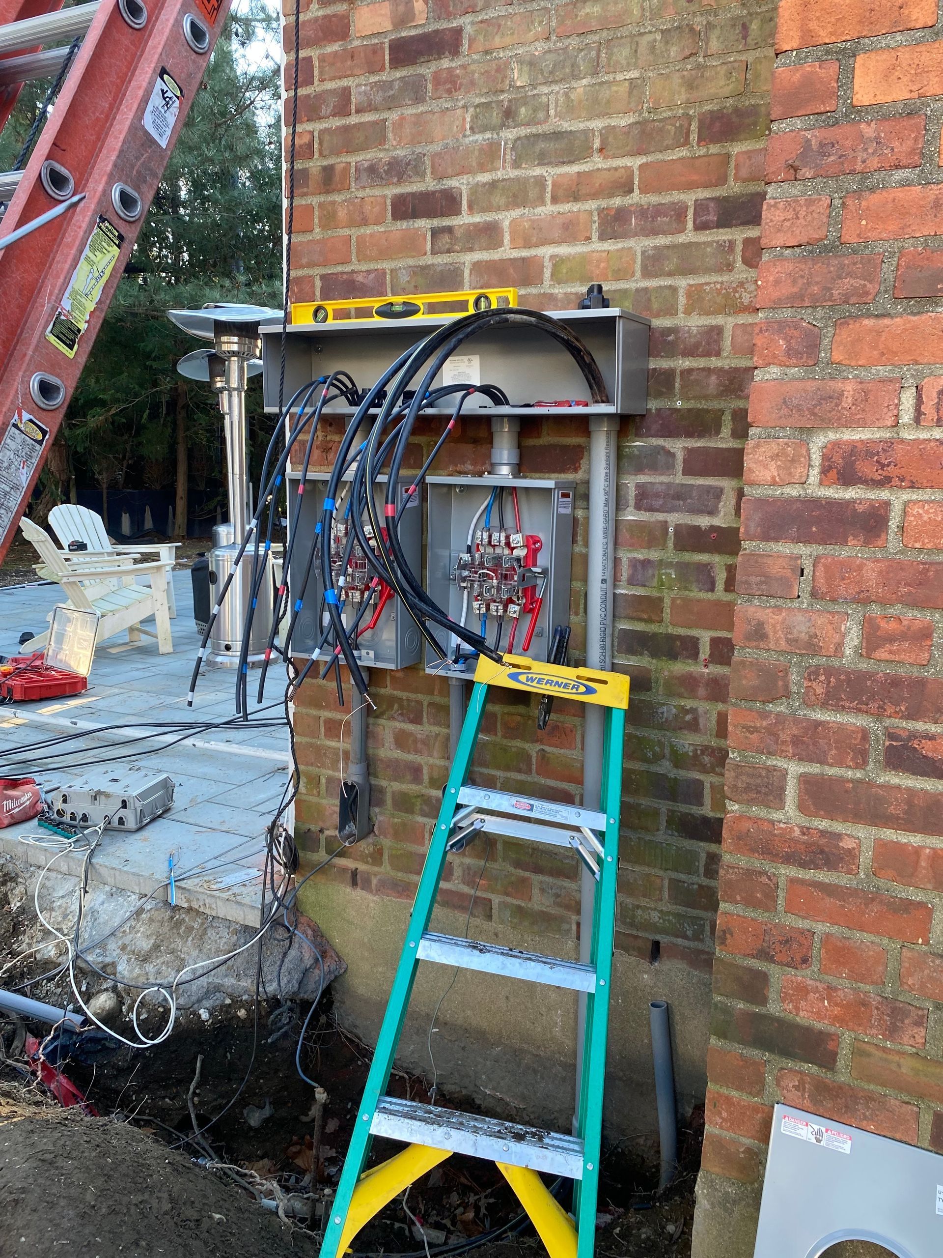 Electrician in blue overalls and hard hat working on wiring in a room.