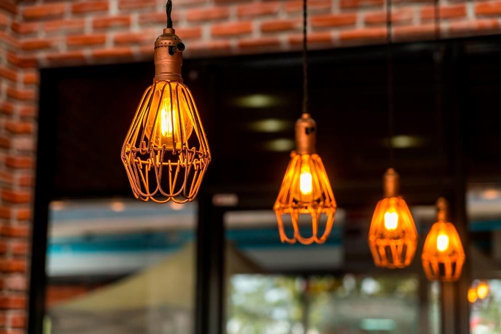 Four hanging pendant lights with wire cages, casting warm light.