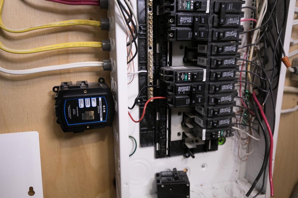 Electrical panel with breakers and attached smart energy monitor. Wires are visible.