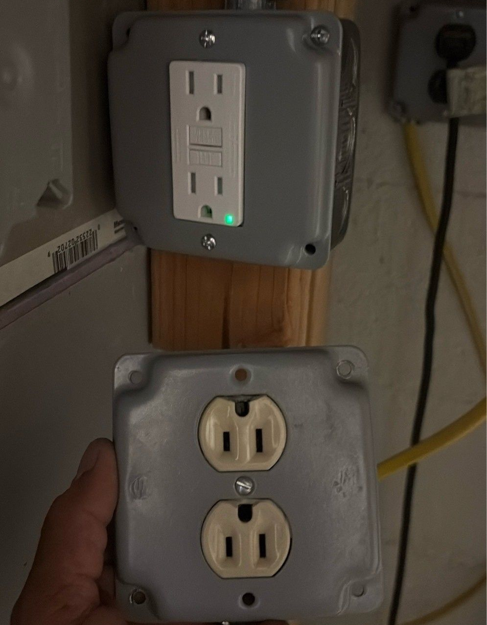 Person installing a light switch on a patterned wallpapered wall.